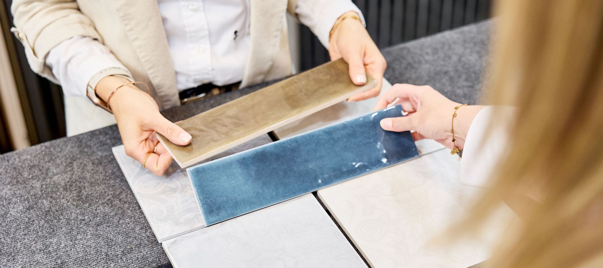 blaue und beige Fliesenmuster werden in der Hand gehalten und dem Kunden zum Fliesenkauf angeboten