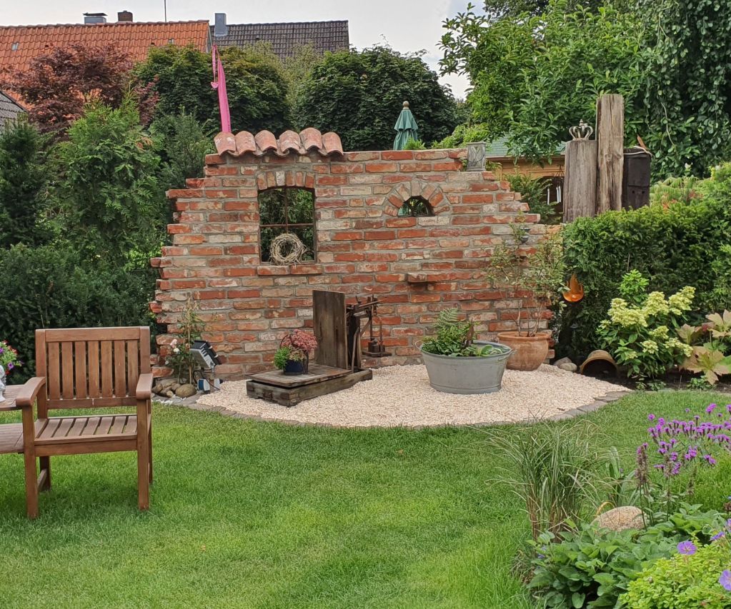 Ruinenmauer aus alten Ziegelsteinen im Garten mit Gussfenster und alten Mönch und Nonnenziegeln