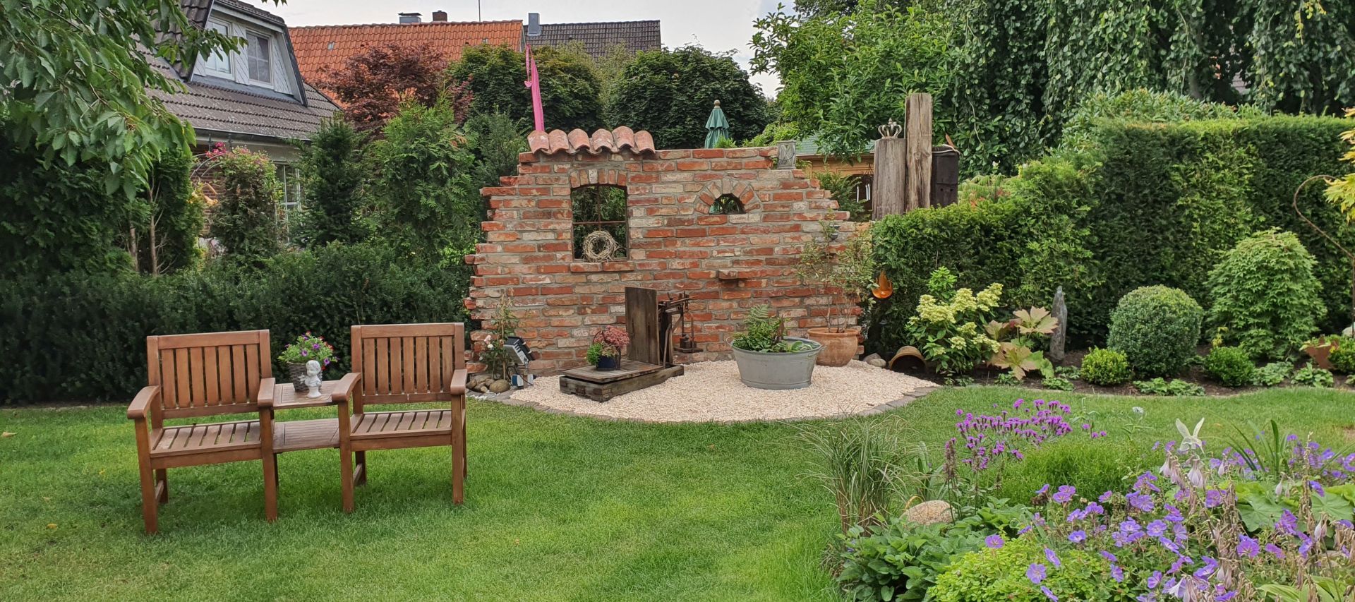 Ruinenmauer aus alten Ziegelsteinen im Garten mit Gussfenster und alten Mönch und Nonnenziegeln