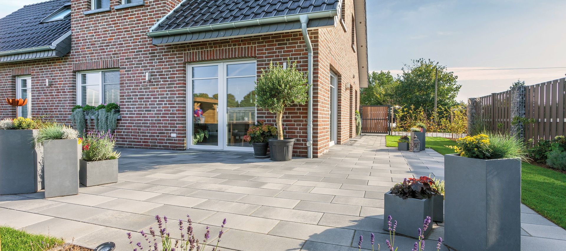 Xline Fintel Betonpflasterstein graphitbunt vor einem Einfamilienhaus mit rotblauen verblender