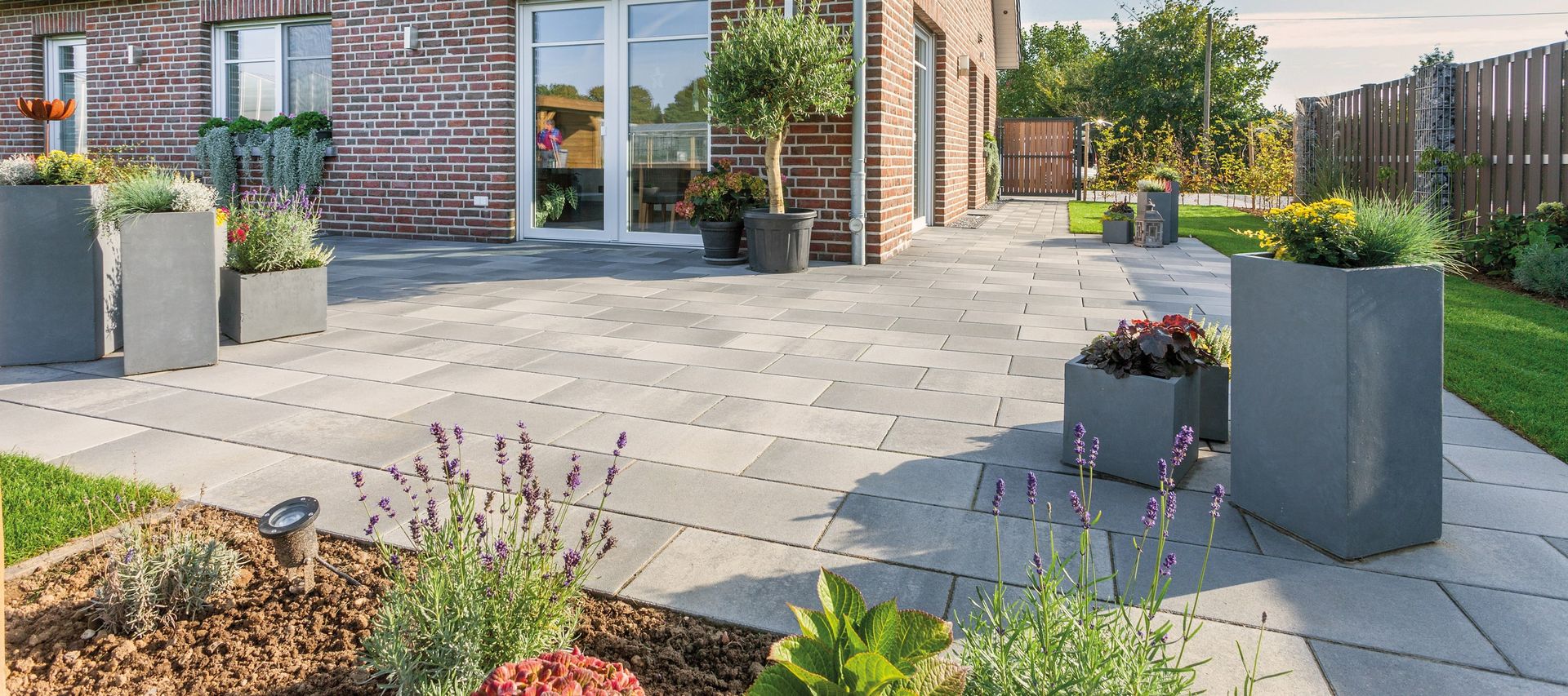 Xline Fintel Betonpflasterstein graphitbunt vor einem Einfamilienhaus mit rotblauen verblender