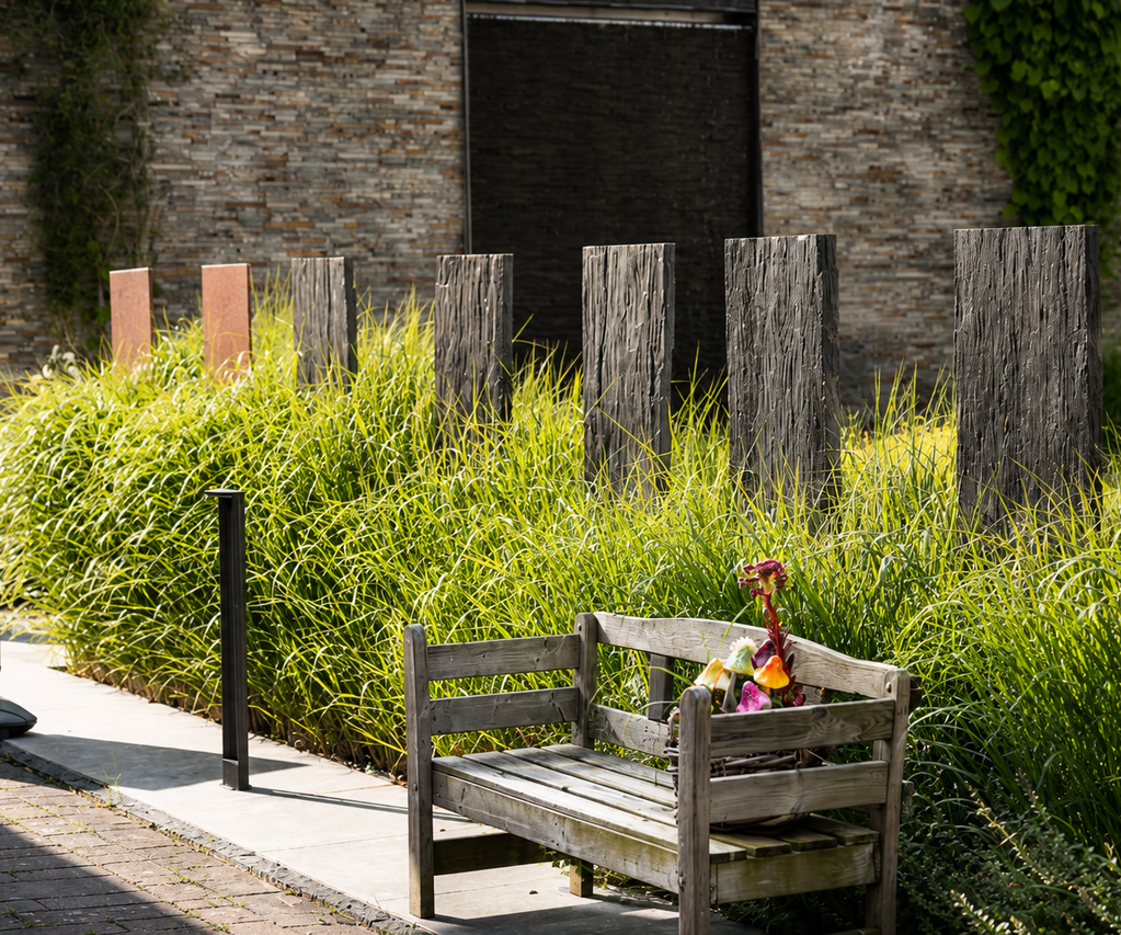 Sichtschutz in Gartenausstellung mit Pflanzen dazwischen. Bank mit Deko steht davor. Garten- und Landschaftsbau bauXpert Gr Beilage Vechta Holz Baustoffhandel