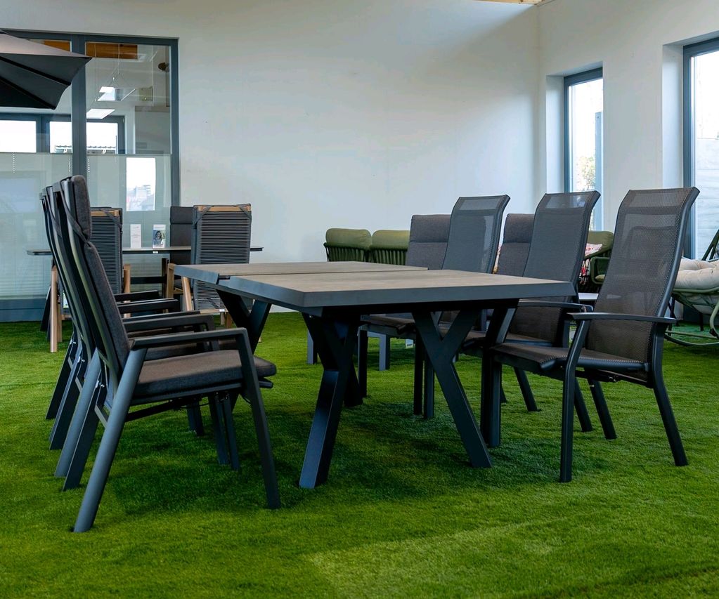 Großer Gartentisch mit mehreren Hochlehner-Stühlen in der Gartenmöbel-Ausstellung.