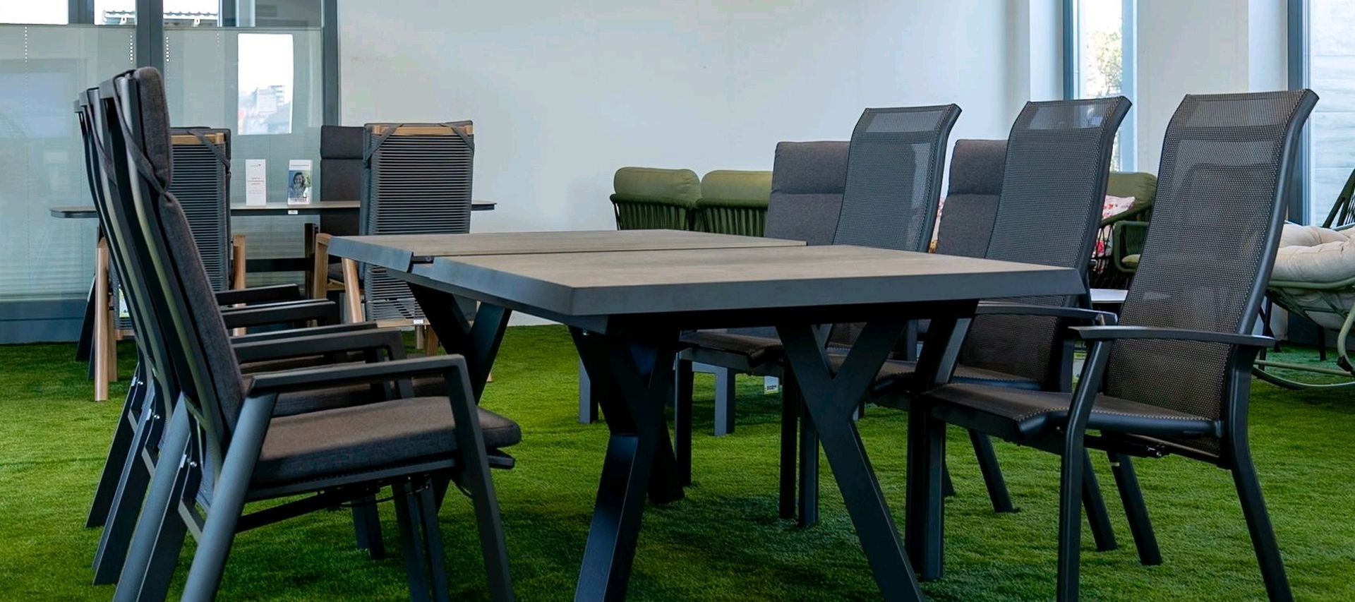 Großer Gartentisch mit mehreren Hochlehner-Stühlen in der Gartenmöbel-Ausstellung.