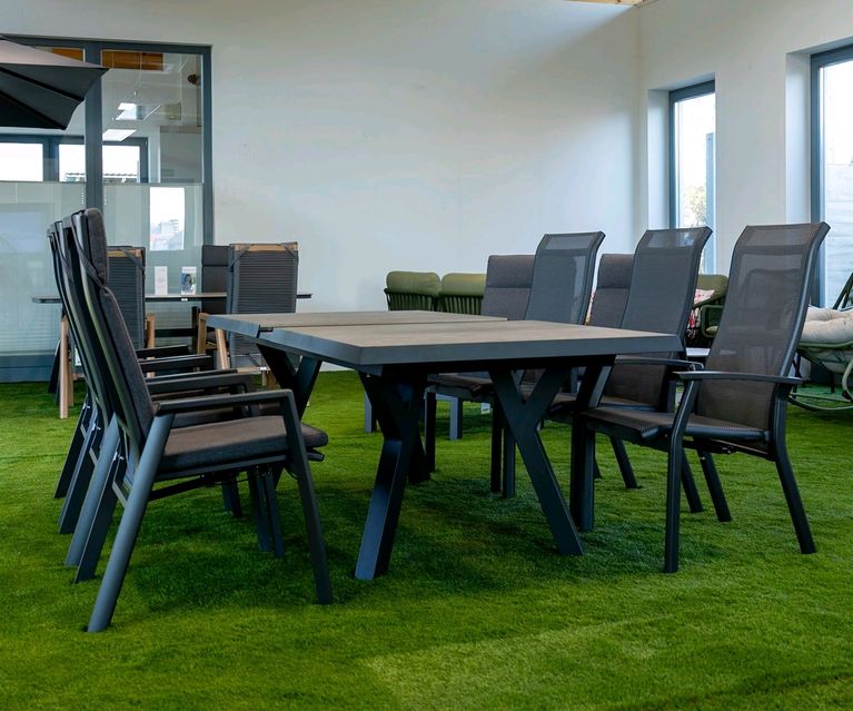Großer Gartentisch mit mehreren Hochlehner-Stühlen in der Gartenmöbel-Ausstellung.