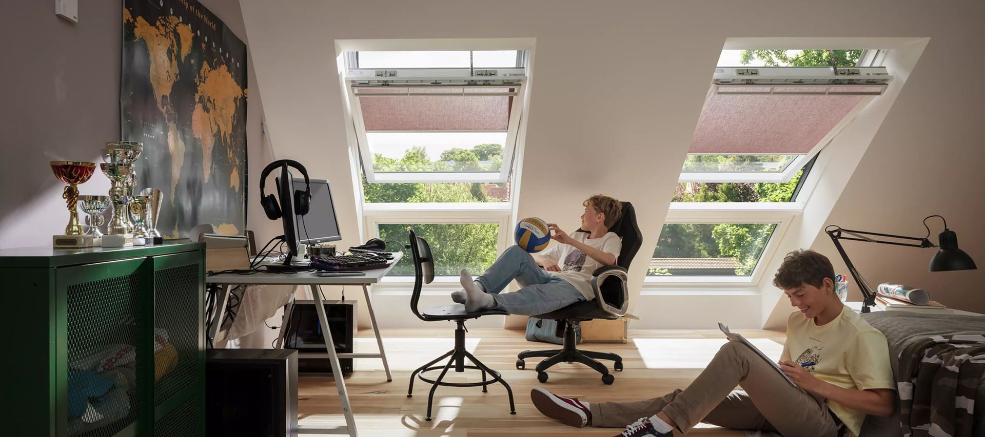 2 Jungs sitzen im Zimmer und chillen. Im Hintergrund sieht man die Velux Dachfenster bauXpert Gr Beilage Vechta Holz Baustoffhandel