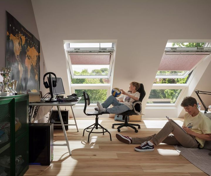2 Jungs sitzen im Zimmer und chillen. Im Hintergrund sieht man die Velux Dachfenster bauXpert Gr Beilage Vechta Holz Baustoffhandel