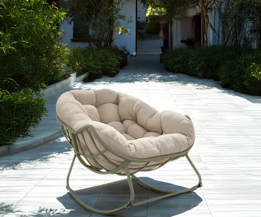 Gepolsterter Loungesessel mit Metallgestell auf einer hellen Terrasse in einem begrünten Innenhof.