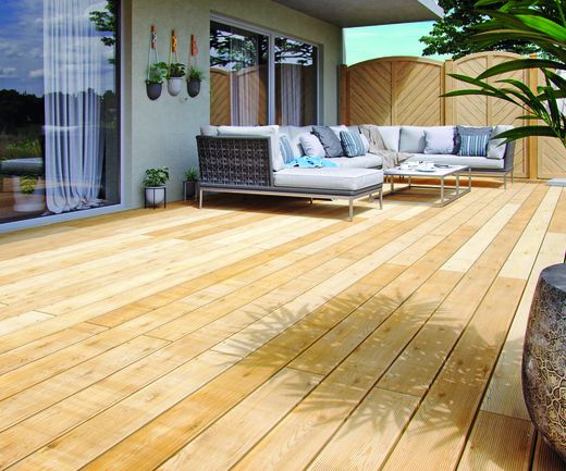 Lärchenholz-Terrasse mit Riffelprofil und moderner Lounge-Ecke im Garten.