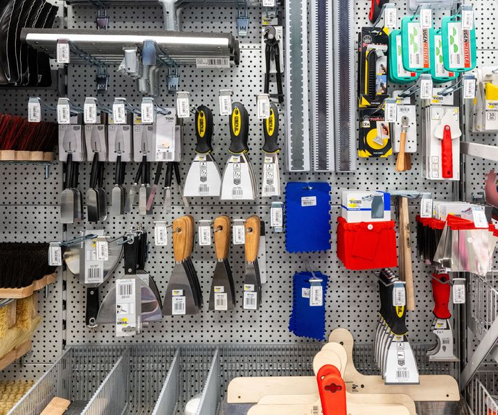 Wanddisplay mit Spachteln, Kellen, Sägen und weiterem Handwerkzeug übersichtlich im Fachmarkt präsentiert.