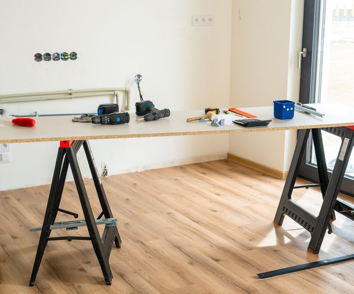 Innenraum mit Arbeitsplatte auf Böcken, Werkzeugen und hellem Holzfußboden während der Renovierung
