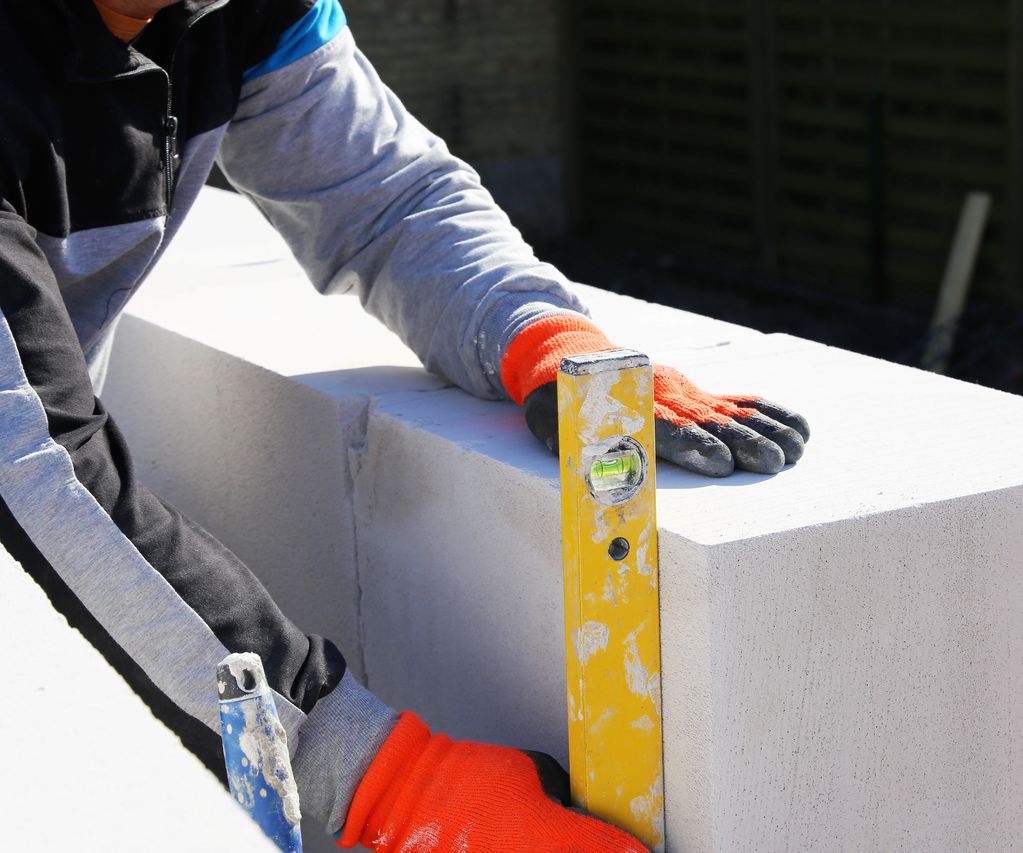 Maurer richtet Porenbetonsteine mit Wasserwaage bei bauXpert gr. Beilage in Vechta aus.