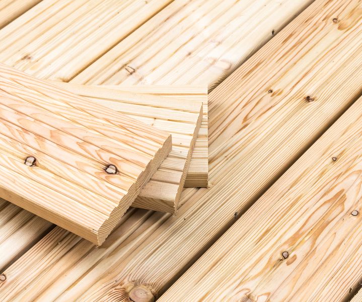 Stapel heller Holz-Terrassendielen mit sichtbarer Maserung auf verlegtem Holzboden