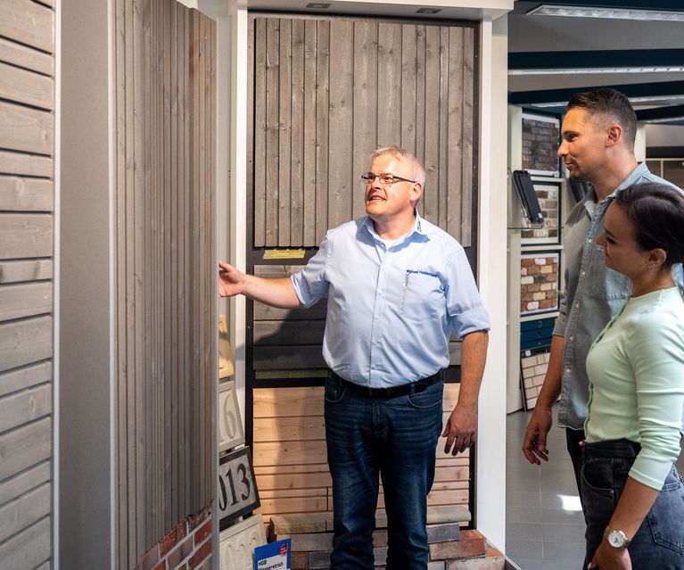 Kundenpaar lässt sich vom Fachberater zur Holzfassade beraten Fassade Holzfassade bauXpert Gr Beilage Vechta Holz Baustoffhandel