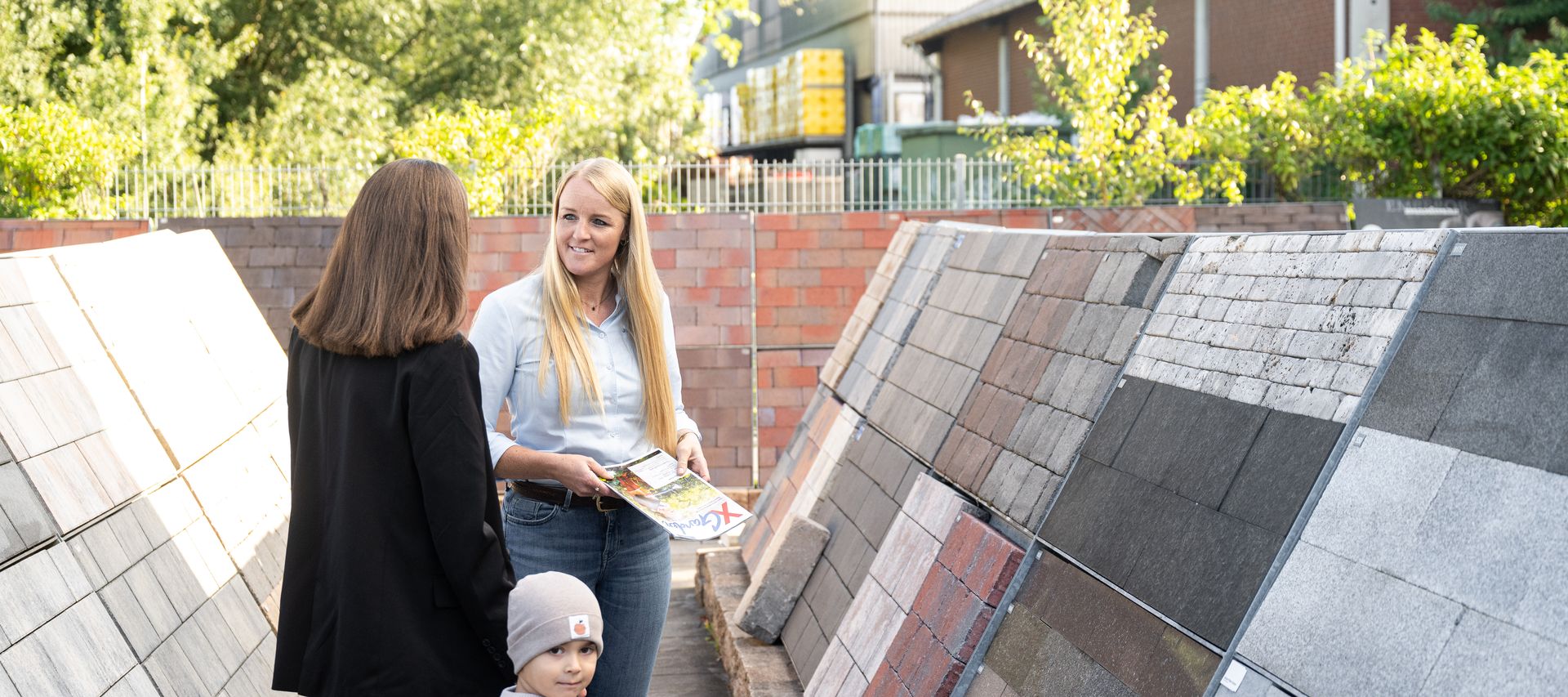 Kundin mit Sohn wird zu Pflastersteinen von Fachberaterin informiert- Beratung Pflastersteine bauXpert Gr Beilage Vechta Holz Baustoffhandel Garten- und Landschaftsbau