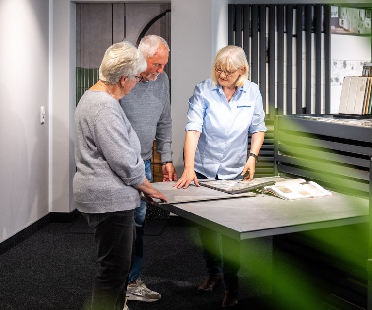 2 Privatkunden werden an einem Fliesentisch von einer Fachberaterin beraten
