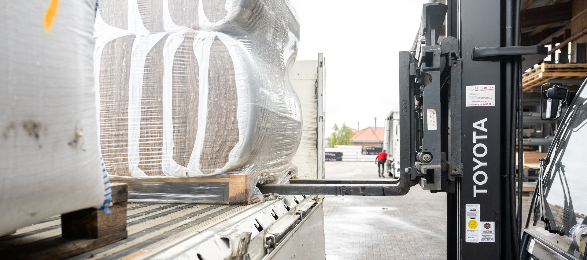 Gabelstapler lädt verpackte Baumaterialien von einem LKW bei bauXpert Gr. Beilage in Vechta ab