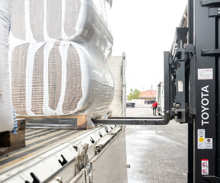 Gabelstapler lädt verpackte Baumaterialien von einem LKW bei bauXpert Gr. Beilage in Vechta ab