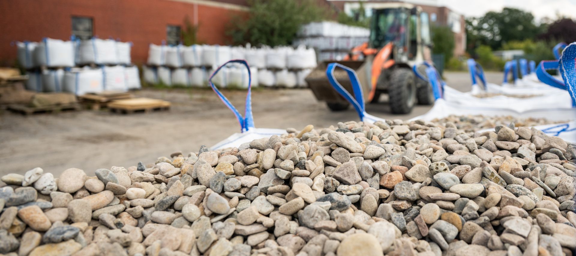 Im Vordergrund Steine/Schüttgüter, im Hintergrund Radlader Radlader bauXpert Gr Beilage Vechta Holz Baustoffhandel