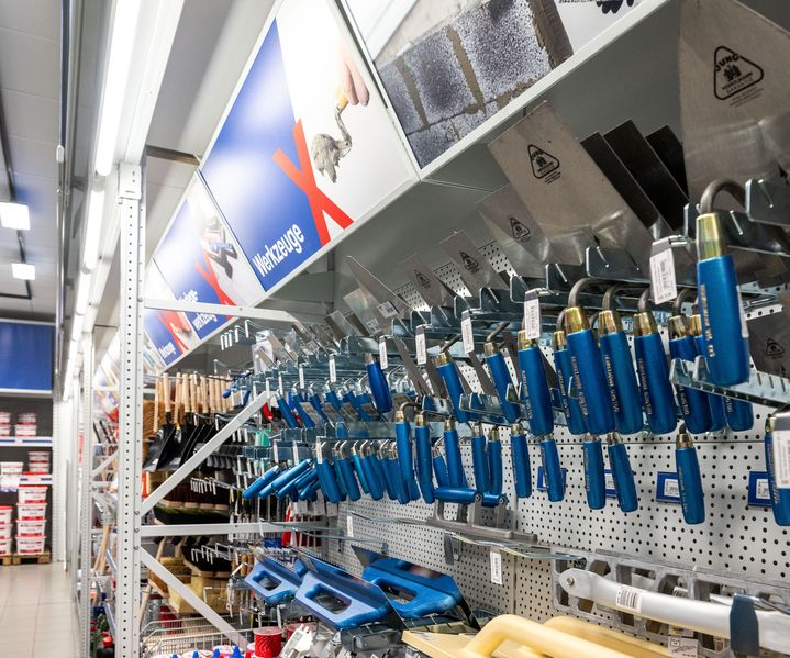 Regalwand mit Kellen, Spachteln und weiterem Maurer- und Putzwerkzeug, ordentlich sortiert im Werkzeugbereich von bauXpert gr. Beilage.