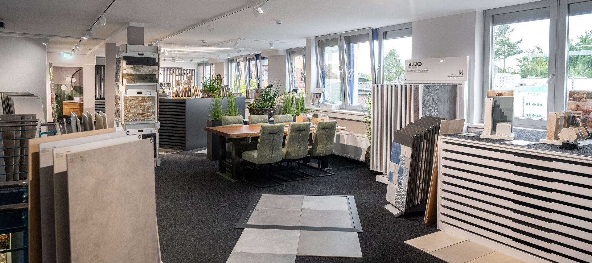 Fliesenausstellung bei bauXpert Gr Beilage in Vechta, dem Holz & Baustoffhandel, verschiedene Fliesen in Aufstellern und auf dem Boden. Gemütliche Sitzgruppe lädt zum Verweilen ein.