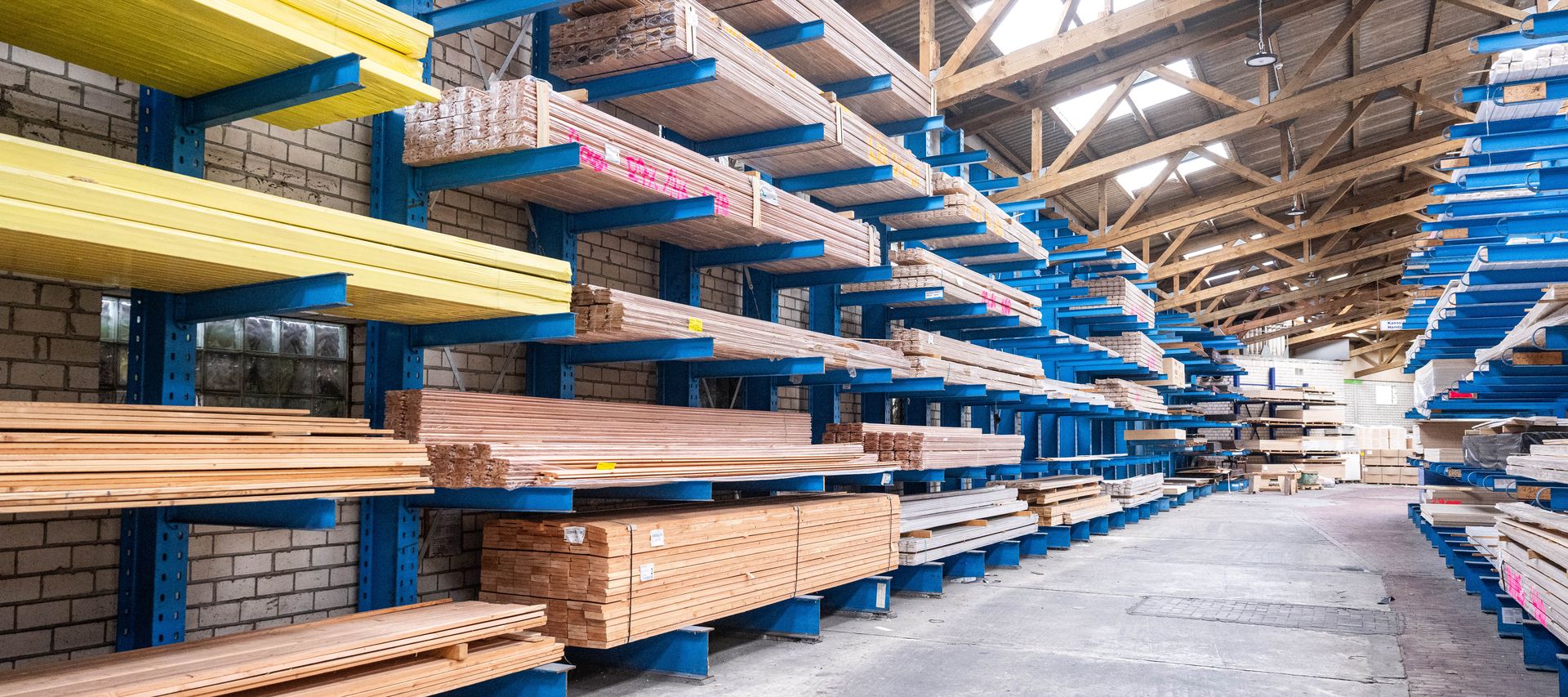 Holzlager von bauXpert Gr. Beilage mit langen Brettern, Leisten und Holzprofilen in blauen Regalen