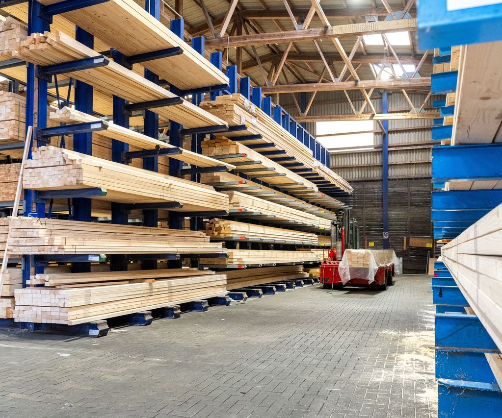 Holzlager von bauXpert Gr. Beilage mit langen Holzbalken in Regalen und Transportwagen im Gang
