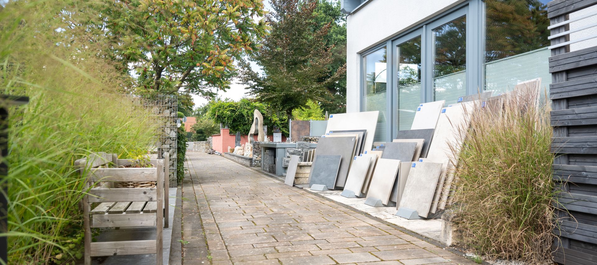 Eingang zur Gartenausstellung bei bauXpert Gr Beilage Vechta mit Kermaikplatten, Zäunen und Wasserspielen im Hintergrund