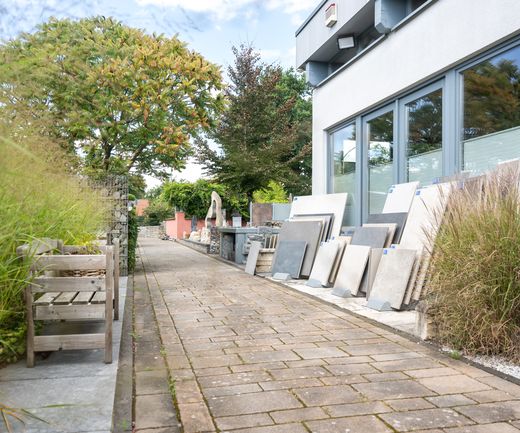 Eingang zur Gartenausstellung bei bauXpert Gr Beilage Vechta mit Kermaikplatten, Zäunen und Wasserspielen im Hintergrund