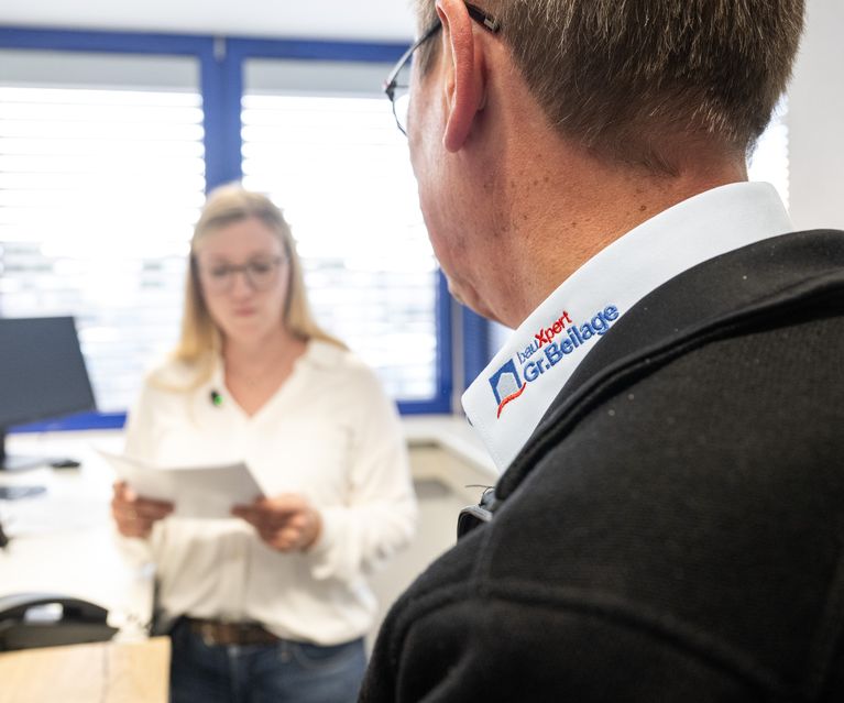 Mitarbeiter im Gespräch mit Kollegin am Empfang bei bauXpert Gr. Beilage in Vechta