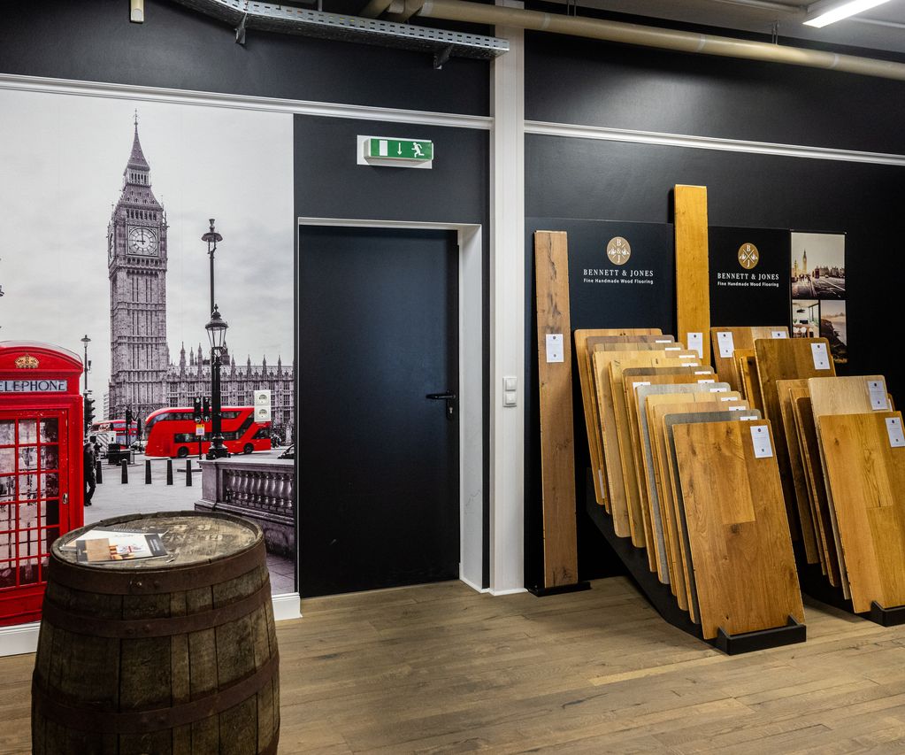 Links eine Wand zum Thema London sowie ein altes Fass. Rechts Echtholz Bodenbeläge bei Bauxpert Gr. Beilage