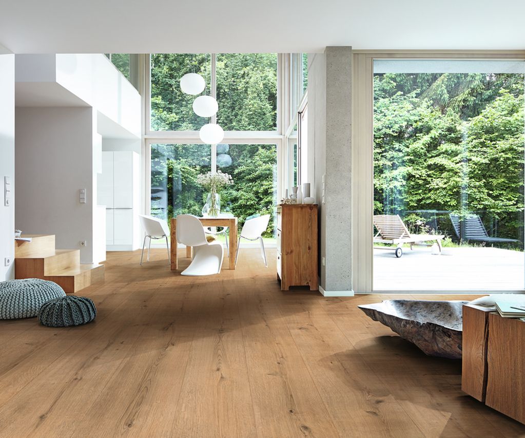 Moderner Wohnraum mit bodentiefen Fenstern und hellem Eichenholzboden, Blick ins Grüne