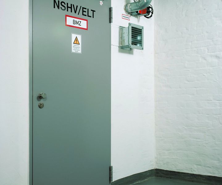 Graue Brandschutztür in technischem Raum mit Lüftungsleitungen