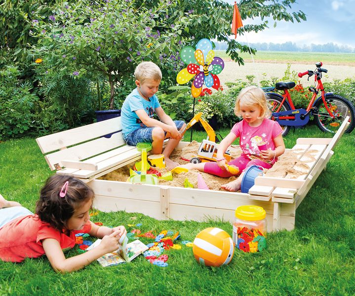 Modernes Gartenhaus aus Holz mit Terrasse, umgeben von Blumenwiese und Gartenmöbeln