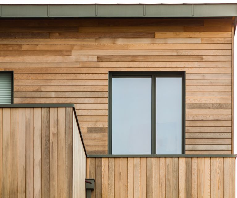Detailansicht einer horizontalen Holzfassade mit Fenster und Balkonbrüstung