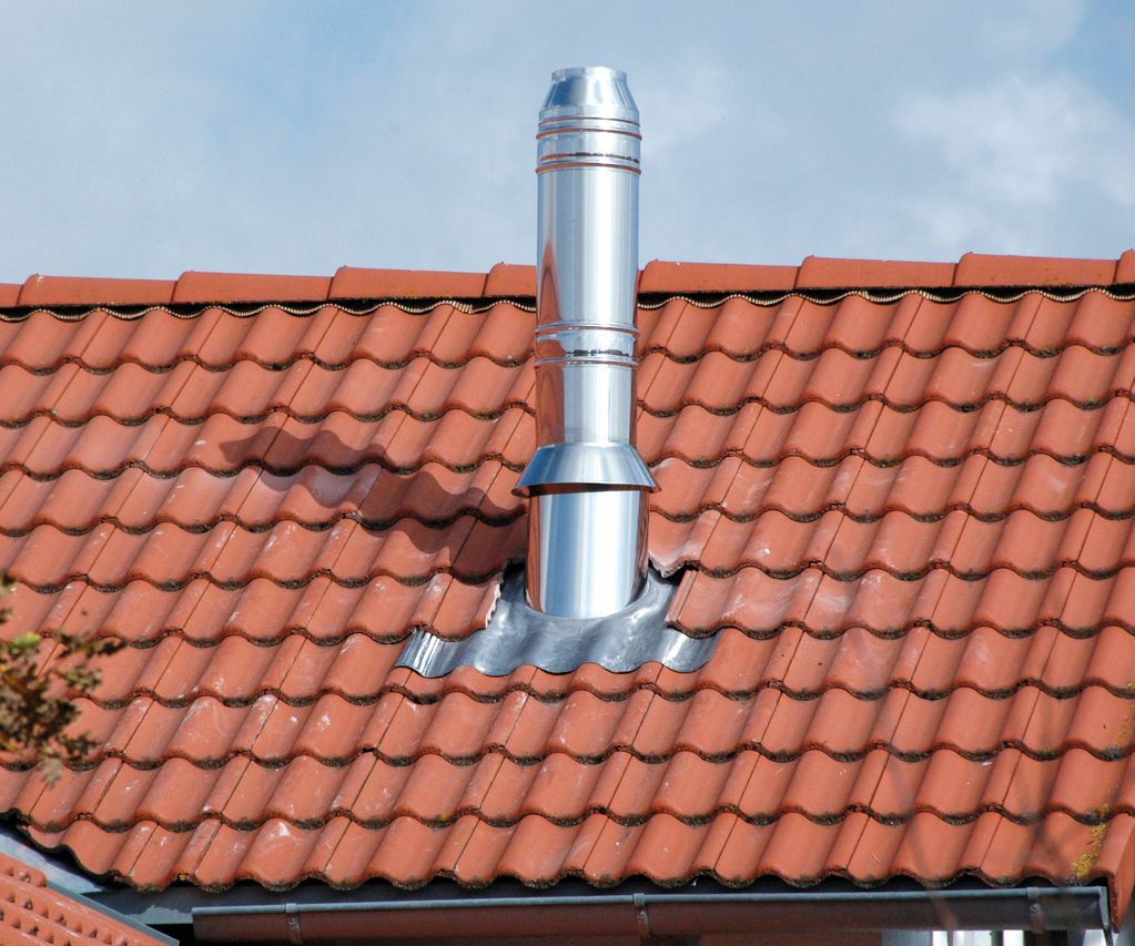 Edelstahlschornstein führt durch ein geneigtes Ziegeldach, sauber eingefasst mit einer Dachabdichtung
