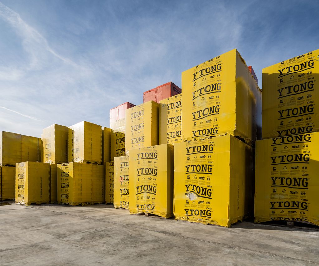 Gestapelte, gelb verpackte YTONG Porenbetonsteine auf dem Baustofflager im Außenbereich