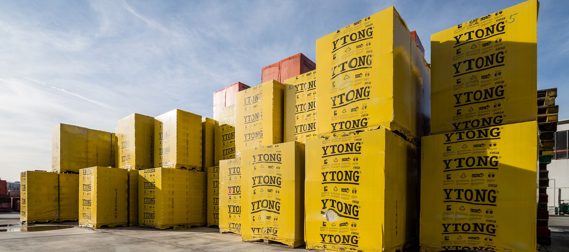 Gestapelte, gelb verpackte YTONG Porenbetonsteine auf dem Baustofflager im Außenbereich