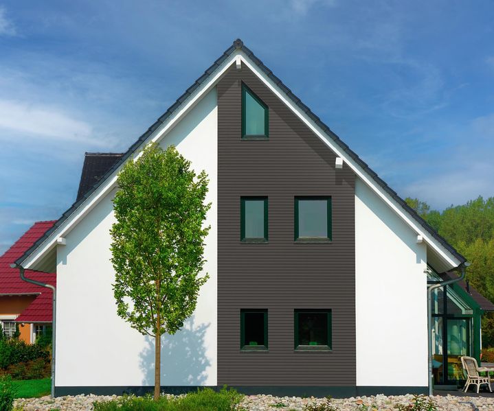Einfamilienhaus mit moderner Fassadengestaltung aus dunklen Fassadenpaneelen aus BPC, kombiniert mit weiß verputzten Flächen. Die klare Aufteilung betont Giebel und Fensterachsen.