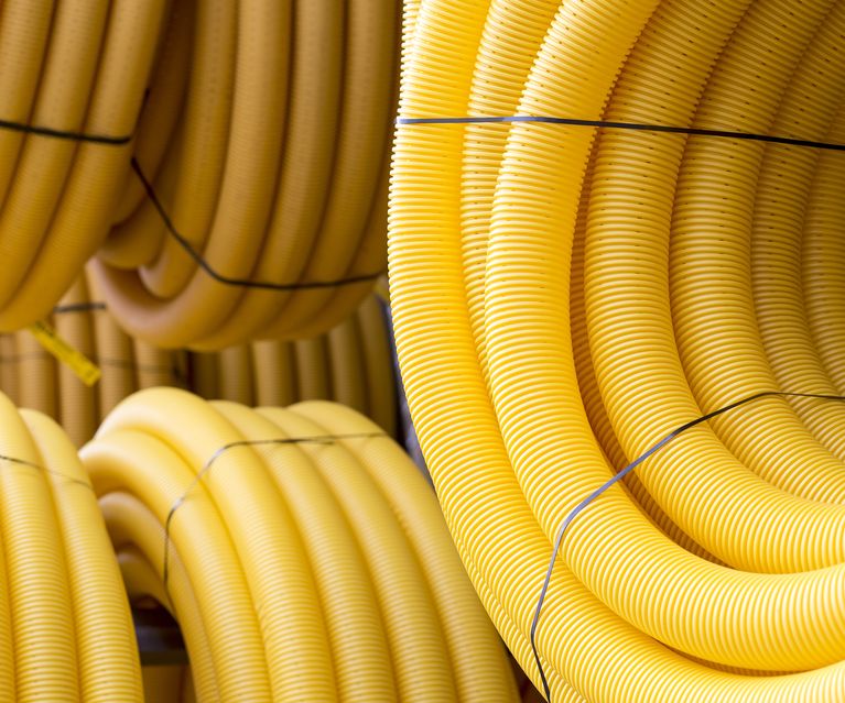 Gelbe flexible Schutzrohre in mehreren aufgerollten Bündeln für Kabel- und Leitungsverlegung