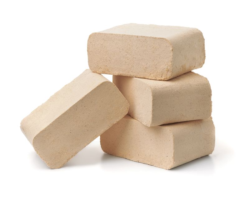 Stapel aus hellen Holzbriketts vor weißem Hintergrund