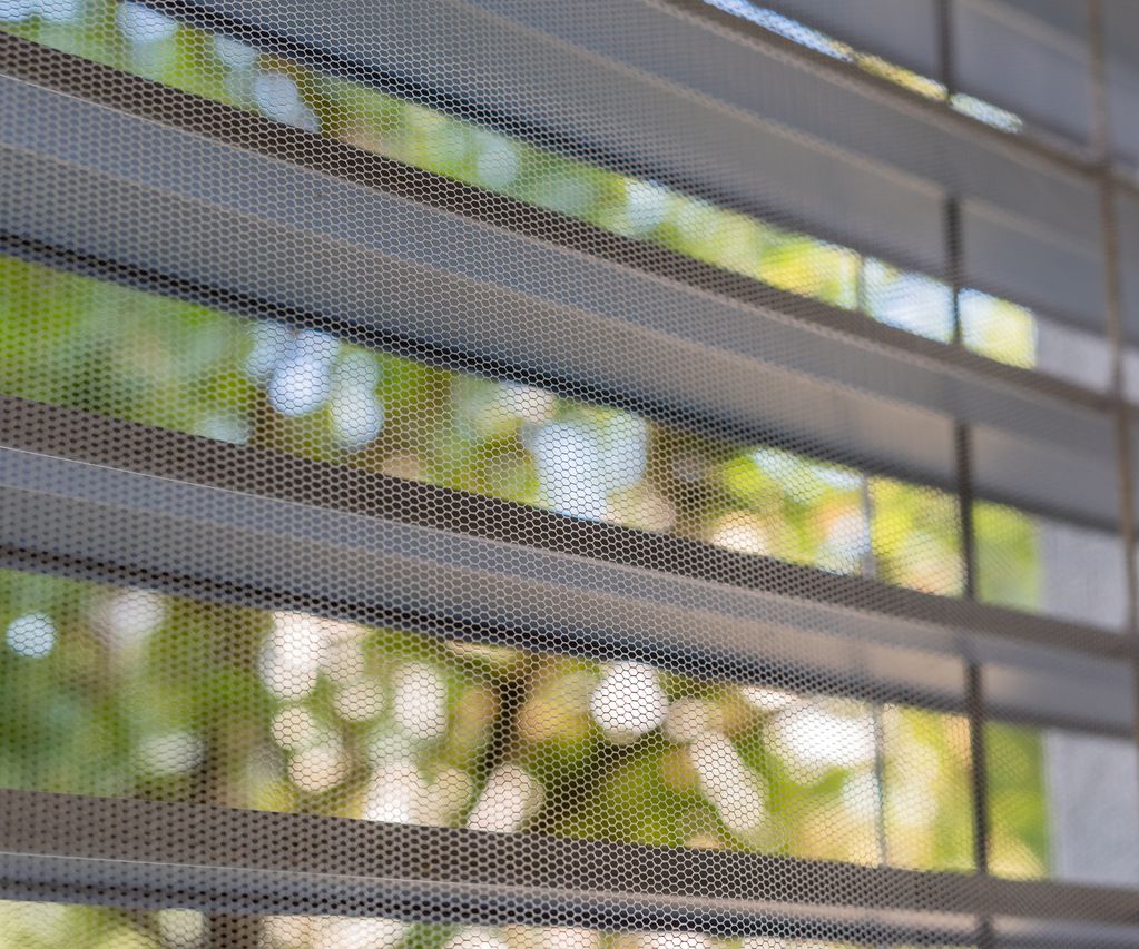 Insektenschutzgitter am Fenster mit Lamellen, Blick nach draußen ins Grüne