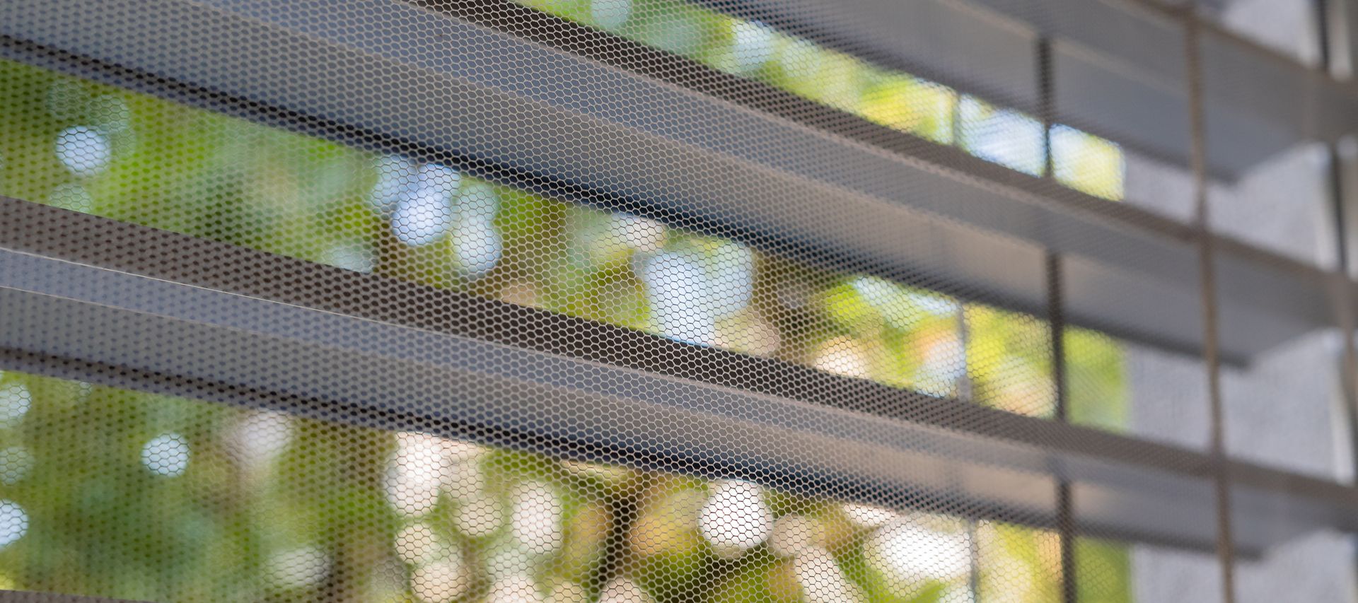Insektenschutzgitter am Fenster mit Lamellen, Blick nach draußen ins Grüne