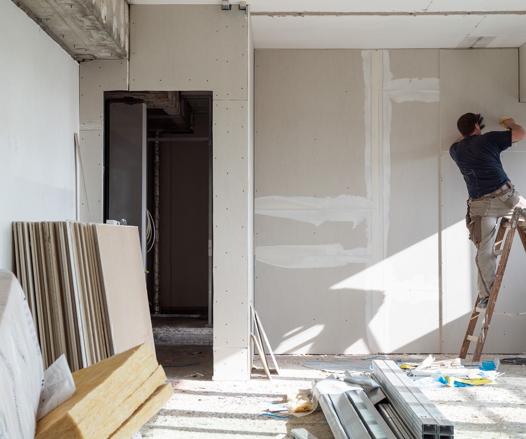 Trockenbauarbeiten im Innenraum, Handwerker montiert Gipskartonplatten an der Wand
