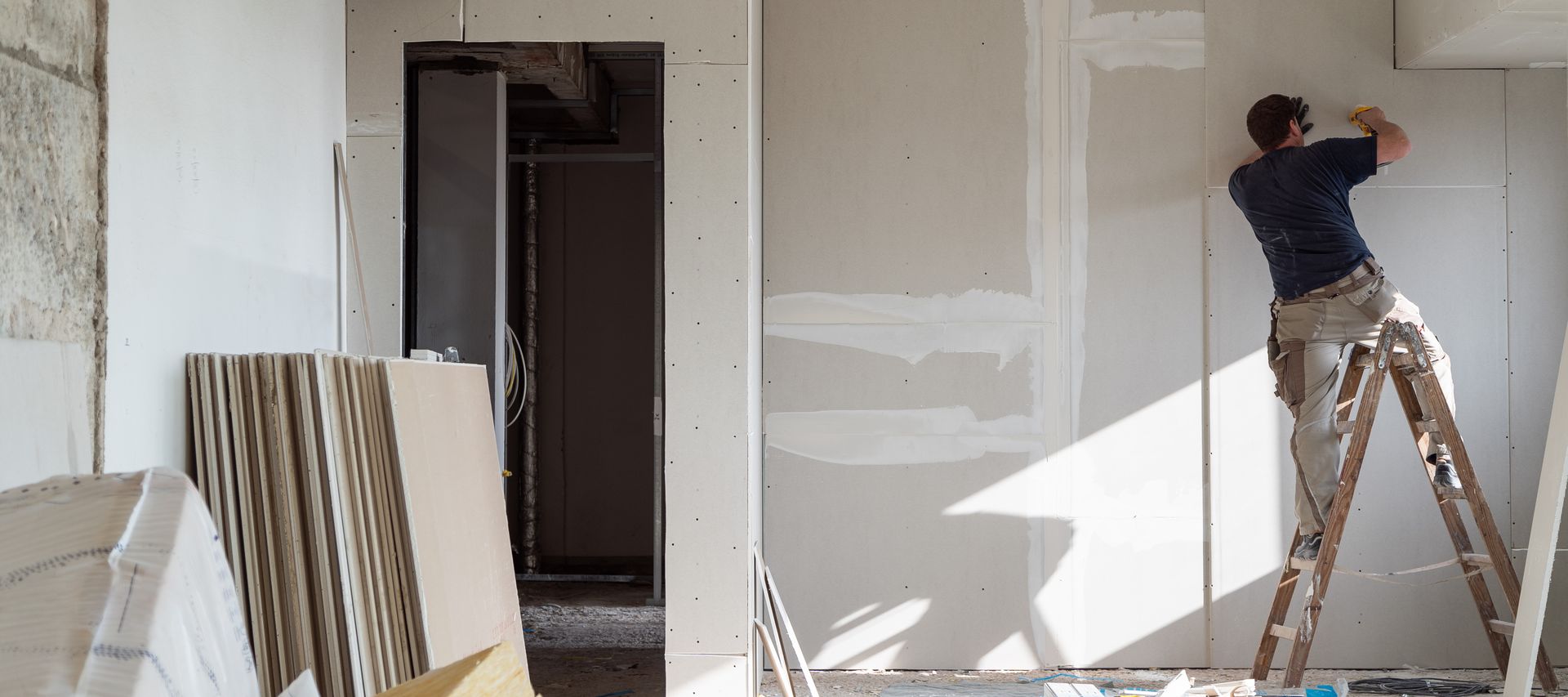 Trockenbauarbeiten im Innenraum, Handwerker montiert Gipskartonplatten an der Wand