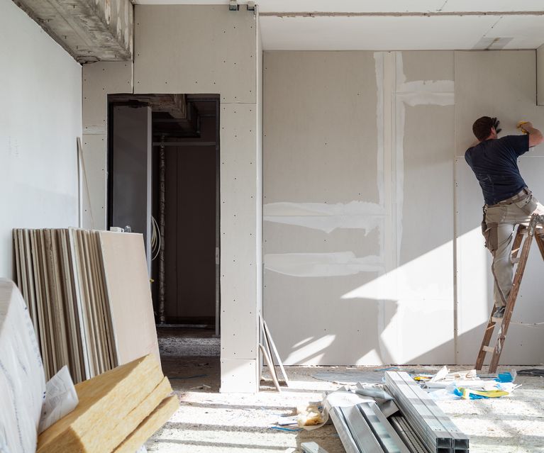 Trockenbauarbeiten im Innenraum, Handwerker montiert Gipskartonplatten an der Wand