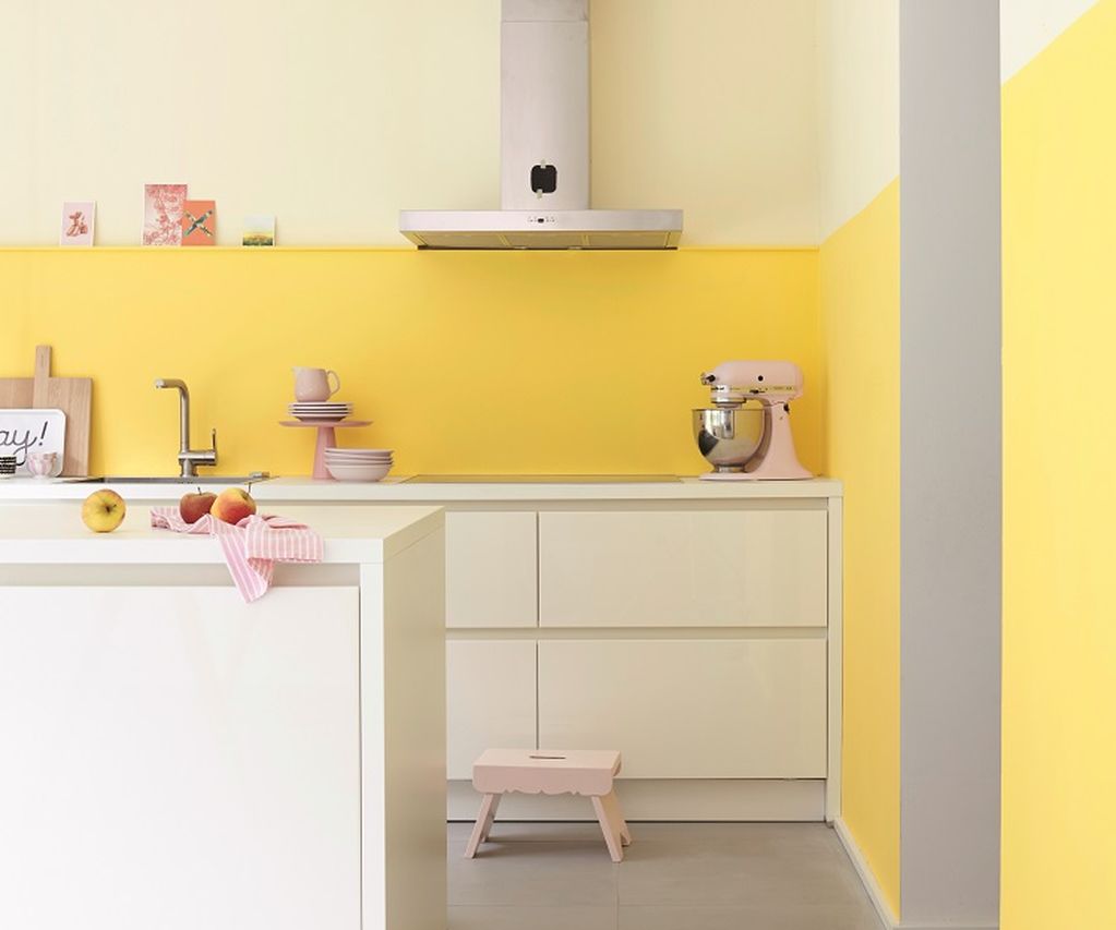 Moderne Küche mit weißer Kücheninsel, gelber Wandgestaltung und klaren Linien in hellem, freundlichem Design.