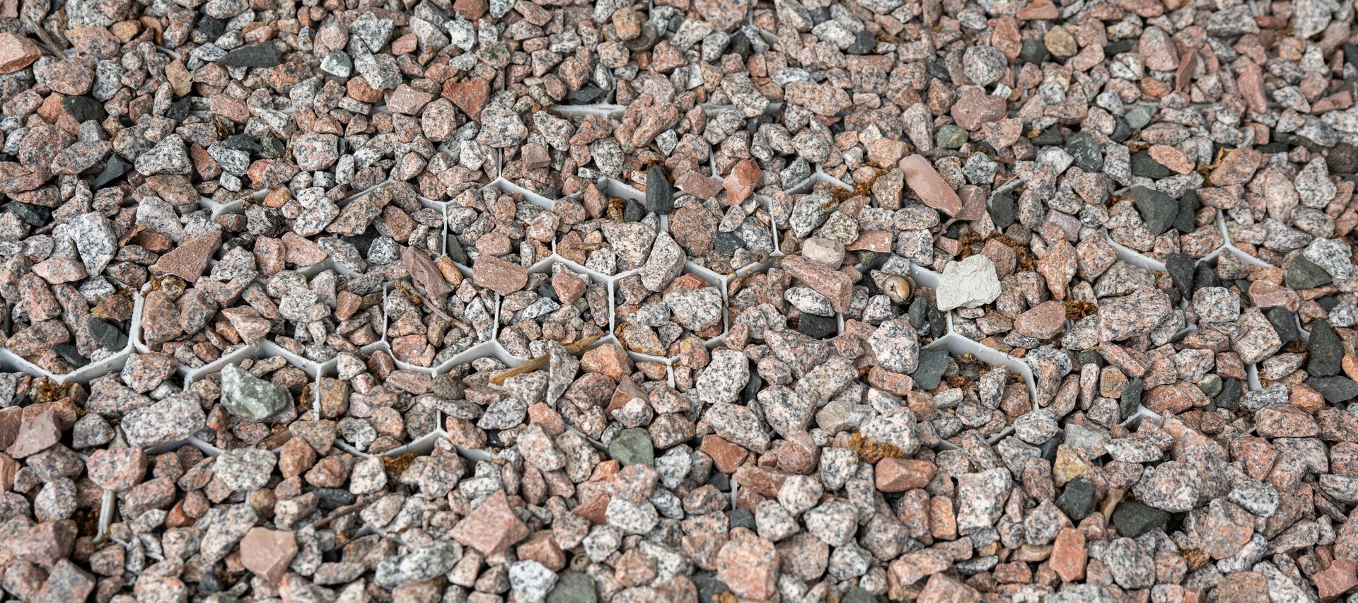 Detailaufnahme von Zierkies in einer stabilen Kunststoff-Wabenstruktur.