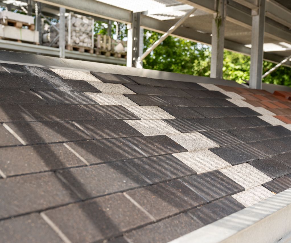 Ausgelegte Pflastersteine in unterschiedlichen Grautönen als Musterfläche.