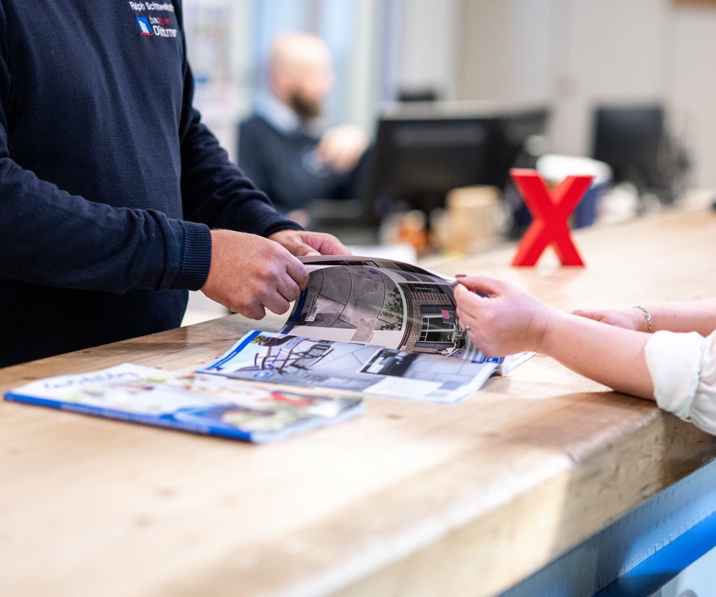 Beratungsgespräch am Tresen bei bauXpert Köhn mit Katalog und persönlicher Fachberatung Titel: Persönliche Beratung bei bauXpert Köhn